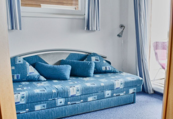 Blauwe slaapkamer met moderne sofa en grote kussens op een woonboot in Duitsland.