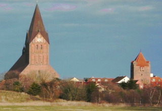 Vista dalla casa galleggiante 'Floating House 2 - Classic / 6 Persons' in Germania verso edifici storici al tramonto.