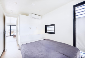 Bright bedroom on a houseboat with a double bed, air conditioning, modern windows, and minimalist decor.