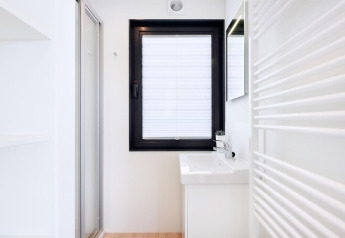 Minimalistische, lichte badkamer op woonboot ‘Fjordblick’ in Duitsland met raam en wastafel.