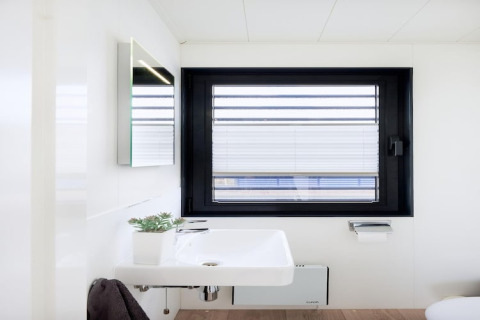 Lavabo moderno da bagno su una houseboat con grande finestra, arredamento minimal e luce naturale.