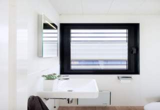 Lavabo de baño moderno en una casa flotante con ventana grande, decoración minimalista y mucha luz natural.
