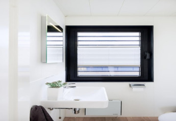 Modern bathroom sink on a houseboat with large window, minimal décor, and natural light coming in.