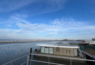 Photo of houseboat 'Fjordblick / 4 Persons' in Germany, docked at a peaceful harbor under a blue sky.