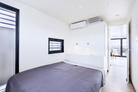 Bright bedroom with double bed and modern decor on houseboat «Fjordblick / 6 Persons» in Germany.