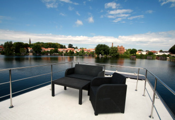 Uitzicht vanaf het dakterras van houseboat Friedrich met tuinmeubels en rivierzicht in Duitsland.