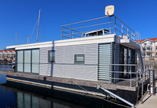 Moderne husbåd Family & Friends LP2 til 1-2 personer i en marina i Tyskland under klar blå himmel.