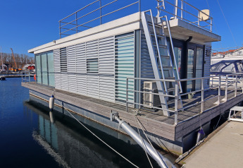 Péniche moderne amarrée au quai sous ciel bleu, Houseboat Family & Friends LP2 en Allemagne, en journée.