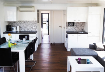 Modern houseboat interior with open kitchen, dining area and a bright living space with corner sofa.