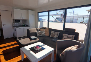 Lichte leefruimte op het woonboot 'Family & Friends LP2' in Duitsland, met zetel, stoel en kitchenette.