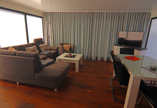 Stue på husbåd Family & Friends LP2 med moderne møbler, grå sofa, tv og store vinduer i Tyskland.