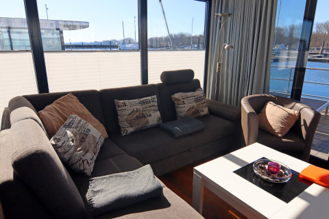 Gezellige zithoek op de woonboot Family & Friends LP2 in Duitsland met zetel en uitzicht op de jachthaven.