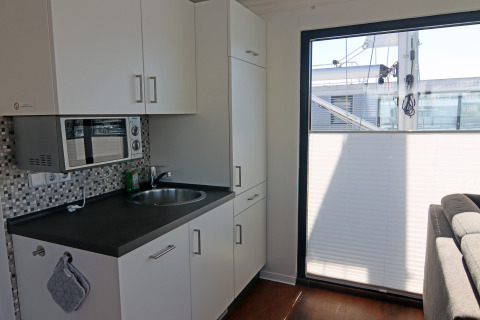 Moderne tekøkken på husbåd med vask, mikrobølgeovn, skabe og stort vindue, Houseboat Family & Friends.