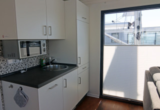 Moderne kitchenette op woonboot met spoelbak, microgolfoven, kasten en groot raam, Houseboat Family & Friends.
