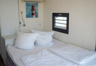 Knusse slaapkamer op woonboot Family & Friends LP2 met tweepersoonsbed, witte kussens en schilderij.