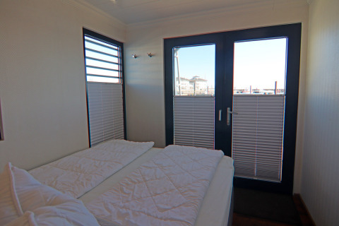 Camera da letto sulla houseboat Family & Friends LP2 in Germania con letto doppio e vista sul porto.