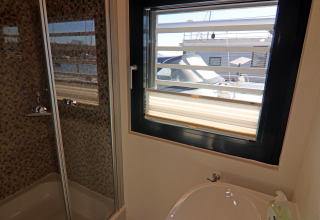 Bagno con doccia e lavandino sulla houseboat Family & Friends LP2 in Germania, vista barche dalla finestra.