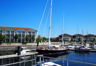 Moderne husbåde og sejlbåde fortøjet i havnen foran lejlighedsbygninger i Tyskland på en solskinsdag.
