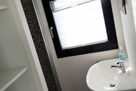 Lichte badkamer op woonboot met lavabo, zeepdispenser en groot raam, Houseboat in Duitsland.