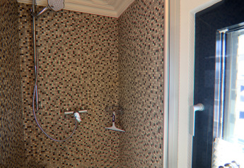 Moderne douche met mozaïektegels en glazen wand op het houseboat Family & Friends in Duitsland.