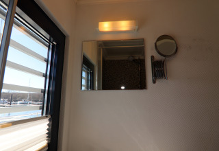 Bagno su una houseboat con finestra, specchio, lampada a parete e vista sul porto in Germania.