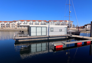 Houseboat 'Family & Friends LP2 / 4 Persons' ormeggiata in un moderno porto tedesco in una giornata di sole.