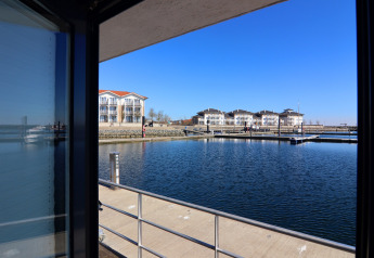 View from the Family & Friends houseboat in Germany with docks, modern buildings, and a blue sky.