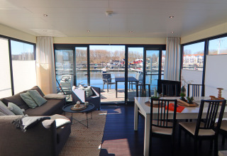 Soggiorno e zona pranzo su Houseboat Family & Friends LP 3 con vista sull’acqua e marina in Germania.