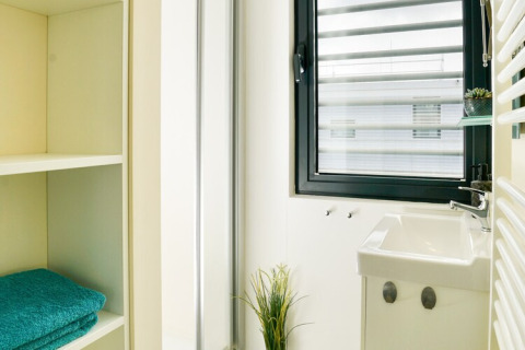 Bagno luminoso e moderno su una casa galleggiante in Germania con finestra, lavabo e asciugamani piegati.