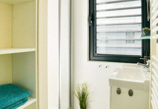 Salle de bain moderne et lumineuse sur une péniche en Allemagne avec fenêtre, lavabo et serviettes pliées.