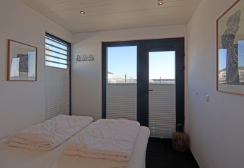 Chambre sur une péniche avec lit double, grandes fenêtres, art moderne et vue sur le port extérieur.