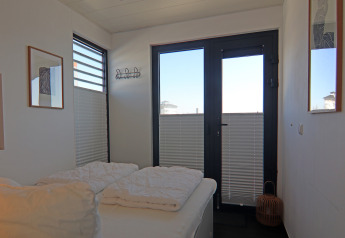 Bedroom on a houseboat with a double bed, large windows, white bedding, and modern wall art.