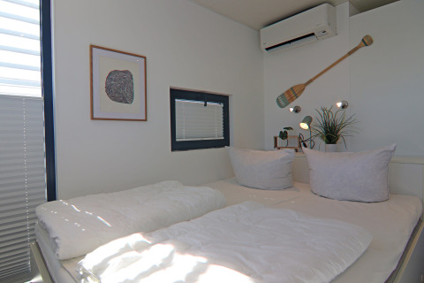Chambre lumineuse et moderne sur une péniche avec lit double, climatisation et décoration élégante.