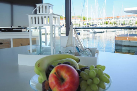 Ciotola di frutta e lanterna su un tavolo con vista sul porto dal Houseboat Family & Friends in Germania.