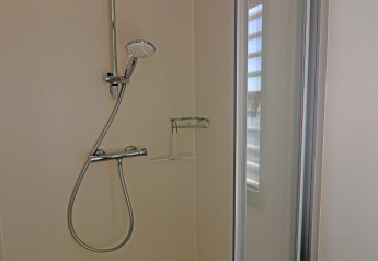 Douche moderne avec pommeau réglable et porte vitrée sur la péniche Family & Friends LP en Allemagne.