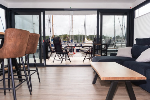 Modern living area on a houseboat with a view of the marina and boats in Germany.