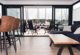 Modern living area on a houseboat with a view of the marina and boats in Germany.