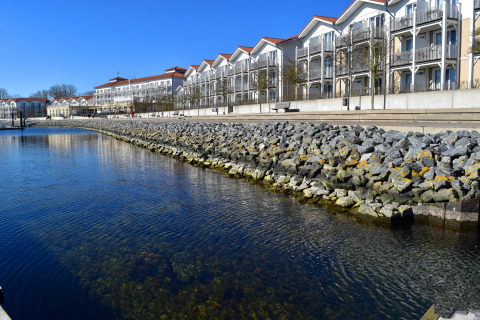 Vue depuis une péniche au quai, avec des bâtiments blancs en arrière-plan et de l'eau bleue en Allemagne.