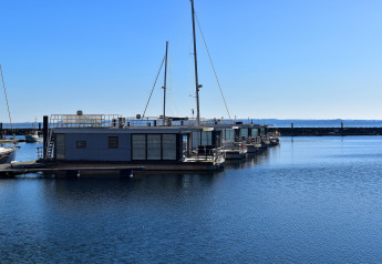 Foto von Hausbooten, die an einem sonnigen Tag mit blauem Himmel in einem ruhigen Hafen liegen.