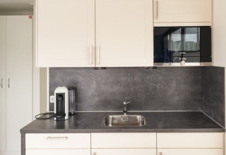 Modern kitchenette on Houseboat “Family & Friends mit Hund LP 10,” featuring sink, microwave, and coffeemaker.