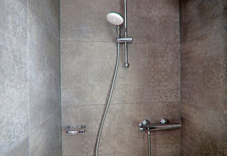 Modern shower area on a houseboat featuring decorative grey tiles and an adjustable showerhead.