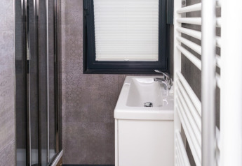 Modernes, schmales Badezimmer auf einem Hausboot mit Waschbecken, Fenster und Duschkabine.