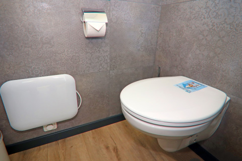 Houseboat bathroom featuring a wall-mounted toilet, toilet roll holder and wood-effect flooring.