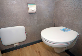 Houseboat bathroom featuring a wall-mounted toilet, toilet roll holder and wood-effect flooring.