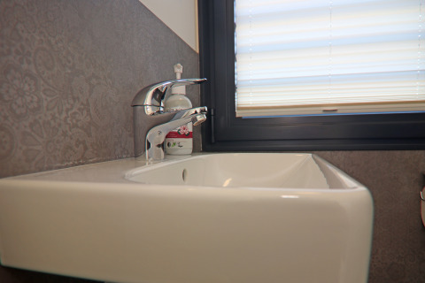 Modern sink with chrome faucet and soap dispenser next to a window on a houseboat in Germany.