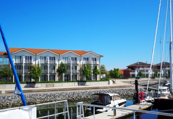 Foto scattata da una casa galleggiante con vista su porto turistico, barche ormeggiate e appartamenti moderni.