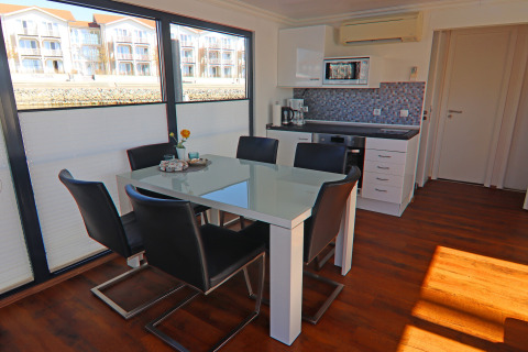 Modern dining and kitchen area on Houseboat 'Family & Friends LP 1/1-2 Persons' in Germany, large windows visible.