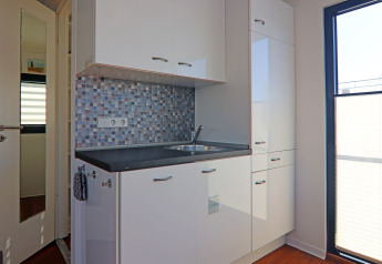 Pequeña cocina moderna en una casa flotante con gabinetes blancos y un salpicadero de mosaico azul.