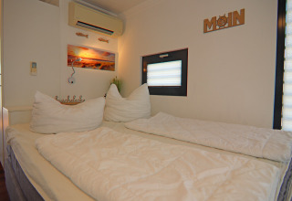 Cozy bedroom on a houseboat with a double bed, window, air conditioning unit, and modern decor.