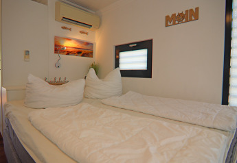 Acogedor dormitorio en una casa flotante con cama doble, ventana, aire acondicionado y decoración moderna.